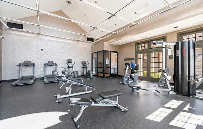 A gym with a variety of equipment including treadmills, weights, and exercise machines.