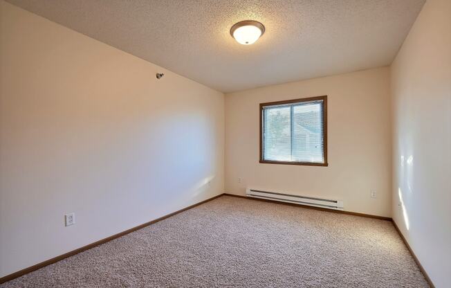 A bedroom with white walls and a window. Fargo, ND Eagle Run Apartments.