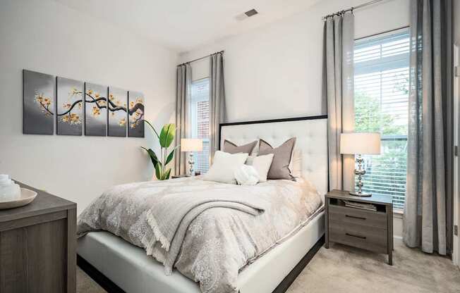 A bedroom with a large bed and a plant on the side table.