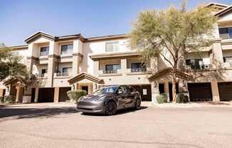 A silver car is parked in front of a multi-story apartment building.