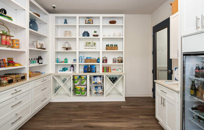 a kitchen with white cabinets and shelves and a refrigerator