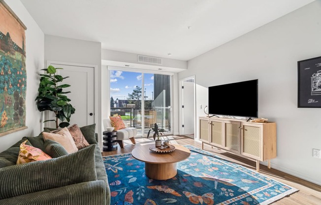 A living room with a couch, a coffee table, and a flat screen TV.