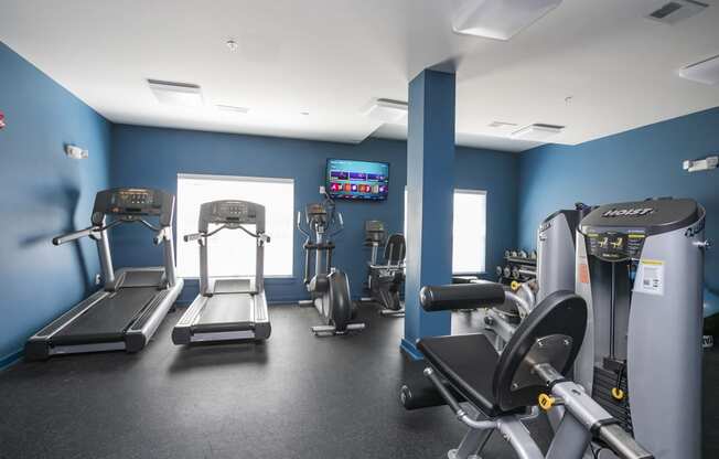 a large fitness room with cardio equipment and a flat screen tv