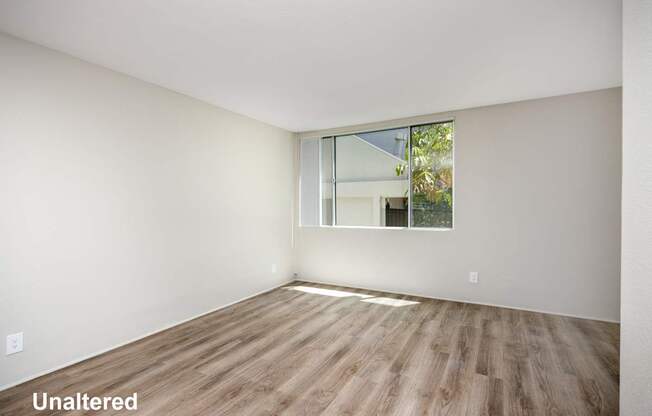 A room with unaltered wooden flooring and a window.