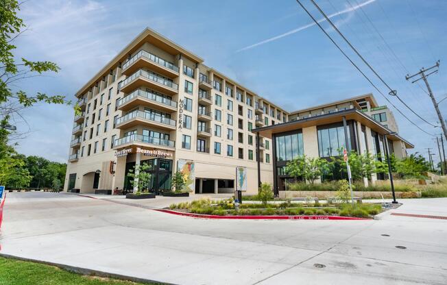 Street-facing Dallas community with ground-level café access, landscaped walkways, and contemporary architecture anchoring a connected neighborhood setting.