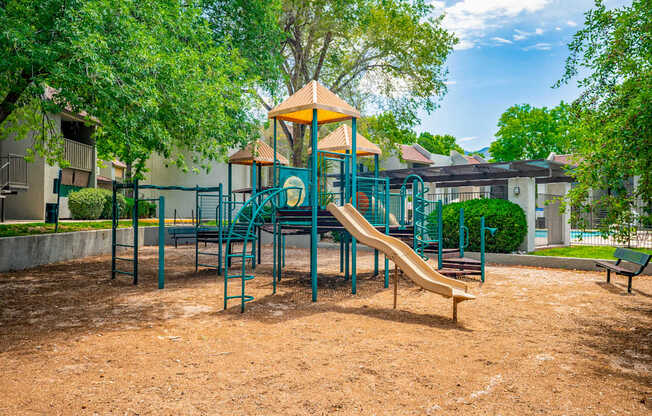 A playground with a yellow and green slide and a green and blue swing set.