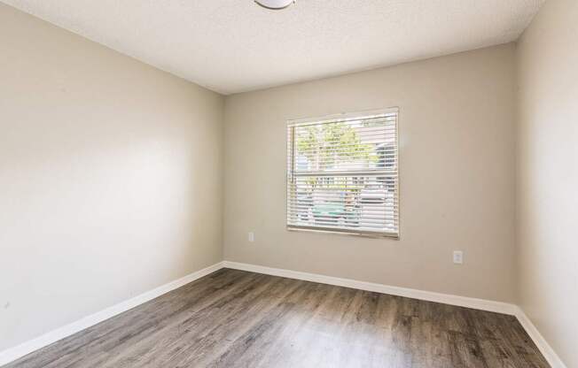 A room with a window and wooden flooring.