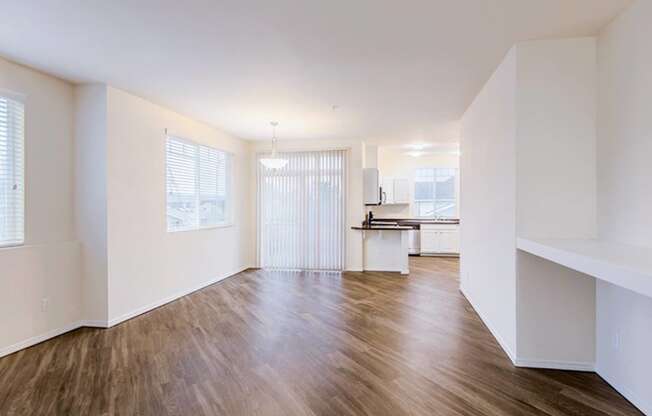an empty living room with hard wood floors and a kitchen