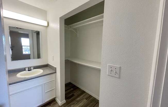 A bathroom with a sink, mirror, and wooden floors.