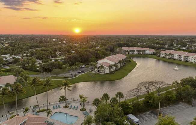 an aerial view of a resort with a lake at sunset