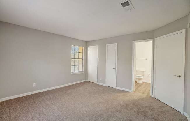 a bedroom with a carpeted floor and a door to a bathroom