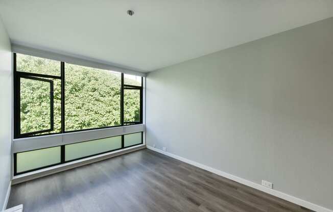 an empty living room with a large window and wood flooring