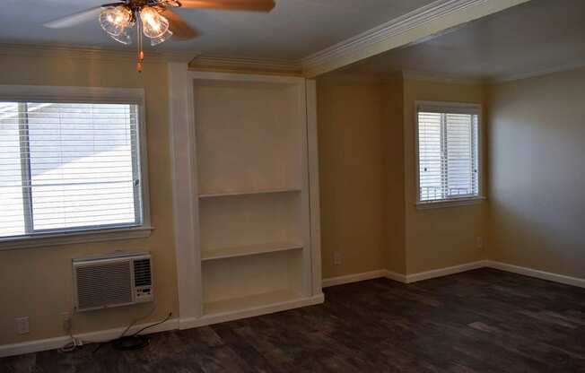 Living room with wood styled ceramic flooring, ceiling fan and windows