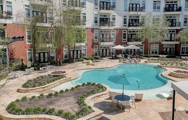 a swimming pool with an umbrella in front of an apartment building
