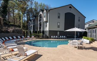 a swimming pool with chairs and umbrellas in front of a building