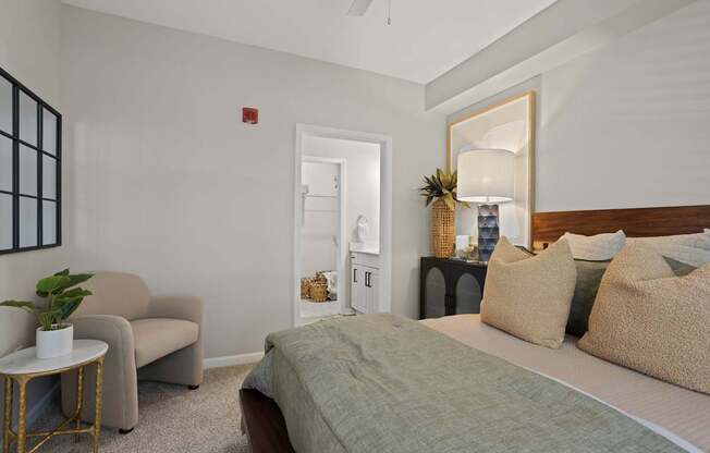 Flatiron West Trade Apartments staged model unit bedroom with gray carpet, attached bathroom with walk-in closet, and a ceiling fan