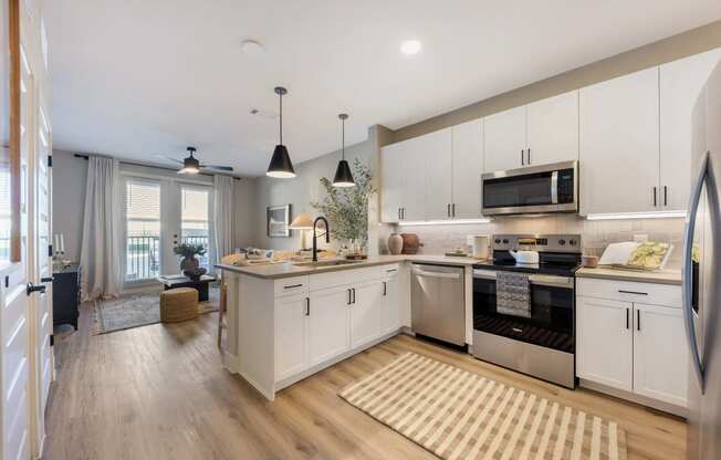 an open kitchen and living room with white cabinets and stainless steel appliances