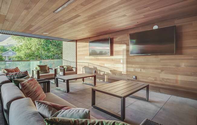 a covered patio with a couch coffee table and tv