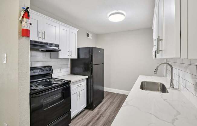 A kitchen with black appliances and white cabinets.
