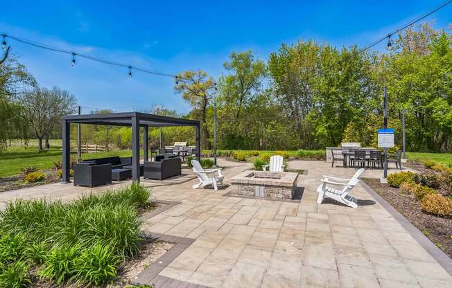 A sunny day at the park with a gazebo, chairs, and a picnic table.