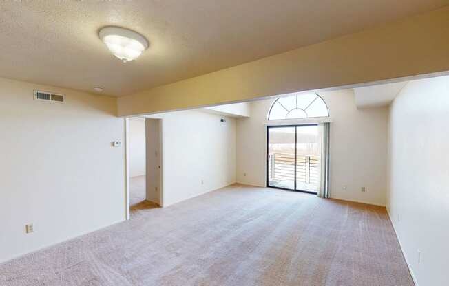 spacious living room with a cathedral ceiling and a door to a balcony