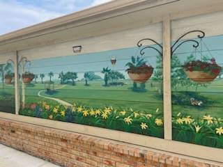 A mural on a wall depicts a garden scene with hanging flower baskets.