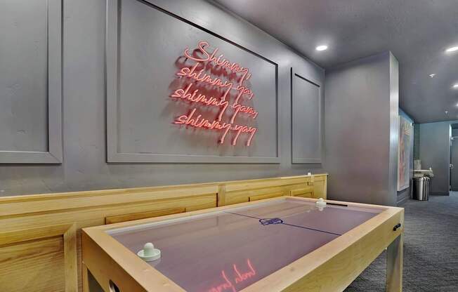 A shiny table with a neon sign on the wall behind it.