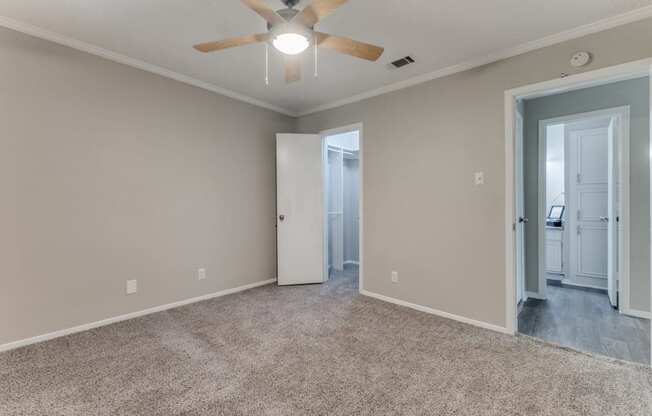 a bedroom with a ceiling fan and a door to a bathroom