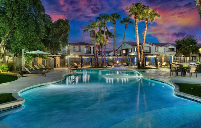 A swimming pool surrounded by palm trees and a house in the background.