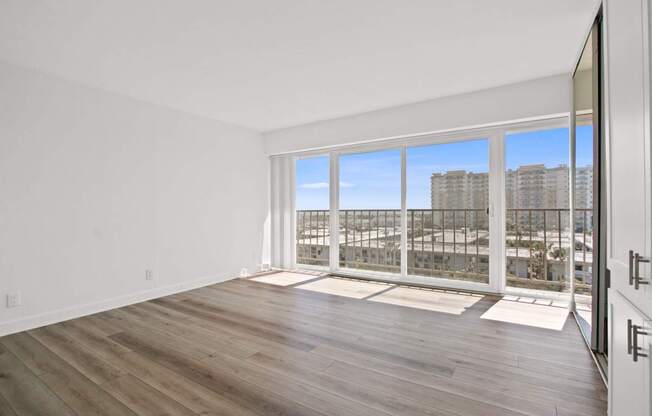 A spacious room with wooden floors and a large window overlooking a cityscape.