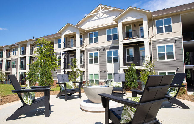 an outdoor area with chairs and tables in front of an apartment building