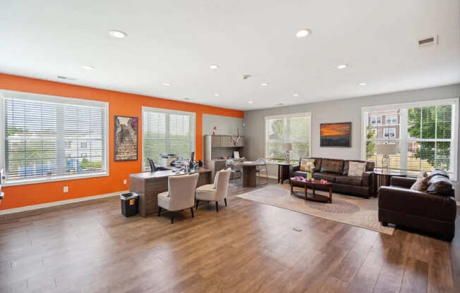 A spacious living room with a brown leather couch and a wooden floor.