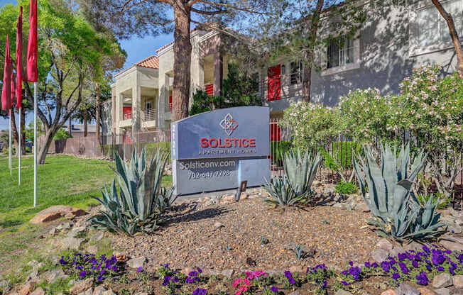 A sign for Solstice Apartments is in front of a building.