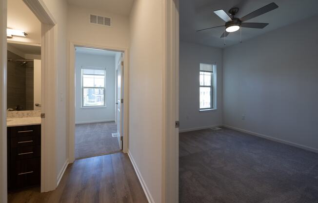 an empty living room with a ceiling fan and a bathroom at The Clearing at ONE28, Olathe, Kansas