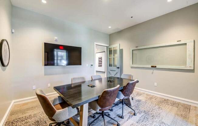 a conference room with a table and chairs and a tv on the wall  at The Vineyards Apartments, California
