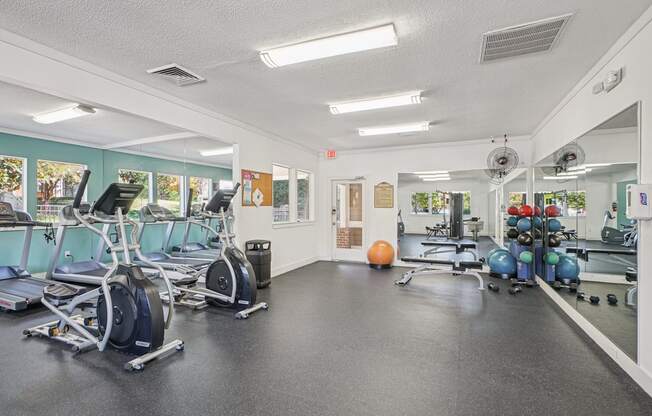 A gym with treadmills, exercise balls, and weights.