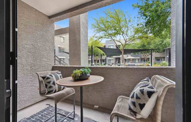 a balcony with two chairs and a small table with a plant on it