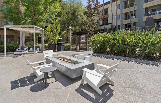 A white outdoor barbecue grill with chairs and a table is set up in a courtyard at The Kitt at Warner Center Apartments, Woodland Hills, California