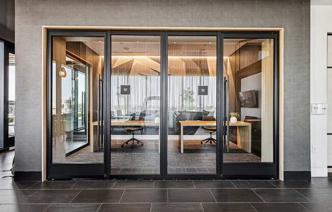 A modern office with glass doors leading to a meeting room.