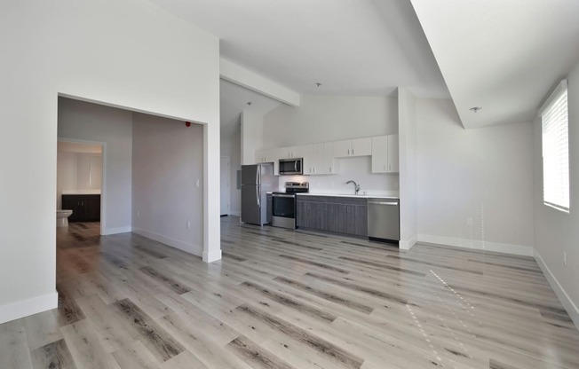 an empty living room with hardwood floors and a kitchen  at Track 281 Apartments, Sacramento