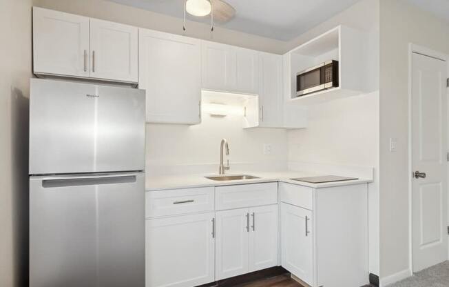 A kitchen with white cabinets and a stainless steel refrigerator.