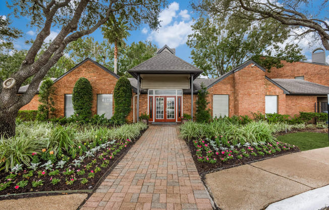 the front of a brick house with a brick pathway and landscaping