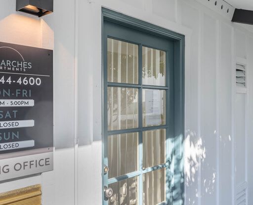 the front door of a white building with a glass door at The Arches Apartments, El Cajon, CA 92021