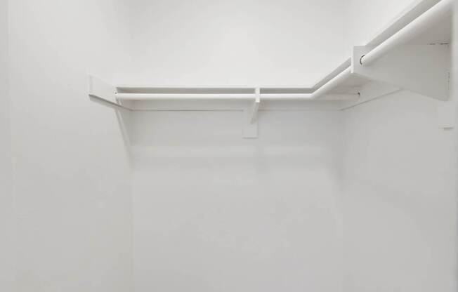 A white hallway with a wooden floor and a door on the left at Verandas Apartments, California