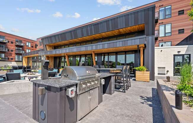 A large outdoor BBQ grill is in the middle of a patio.