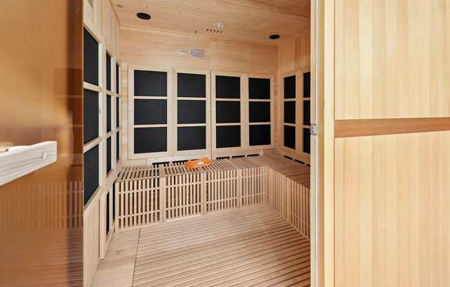 A room with wooden walls and floor and a bench in the middle.