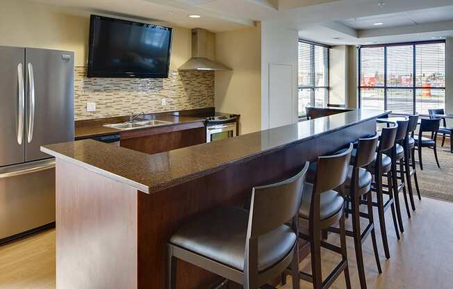 community kitchen with stool seating facing a large TV mounted on the wall