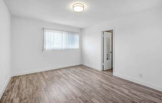 an empty living room with white walls and wood flooring