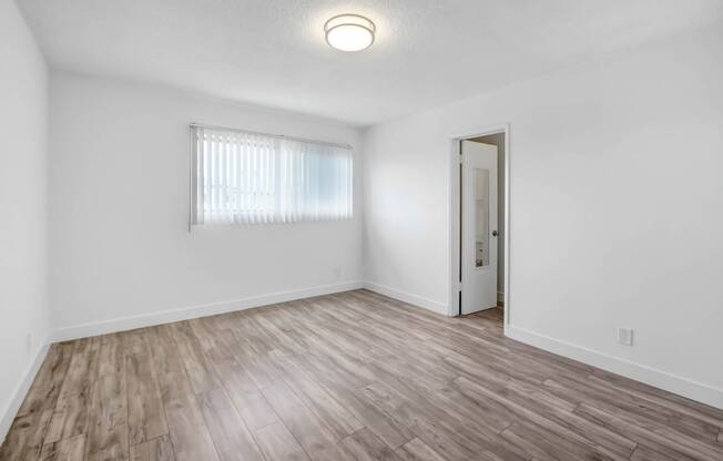 an empty living room with white walls and wood flooring