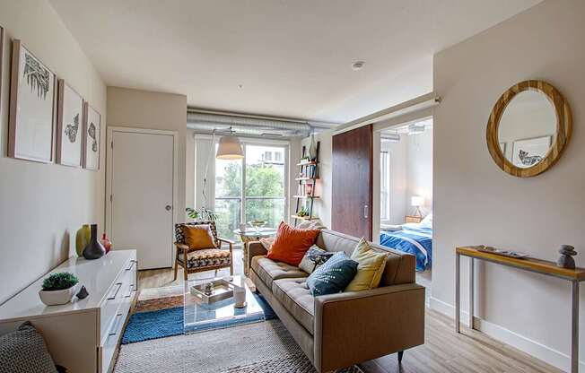 A living room with a couch, chair, and a mirror on the wall.